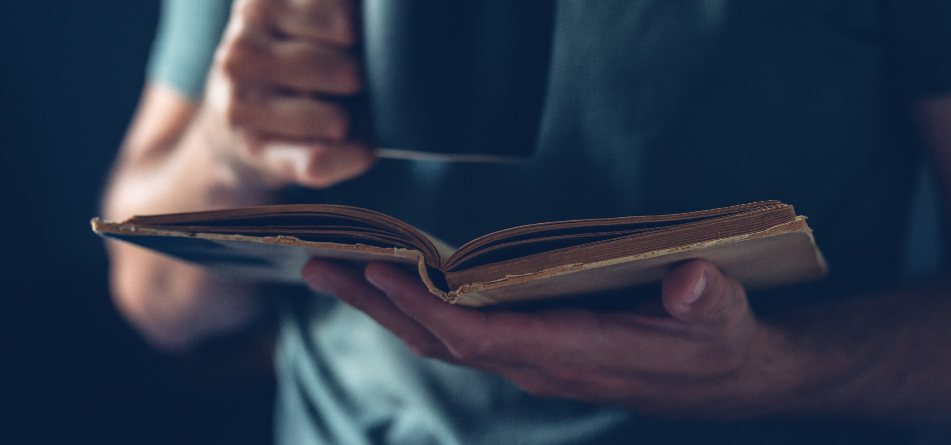 Stylized image of man holding an old book and sipping from a coffee cup